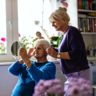 A female assisting a senior woman in preparing herself