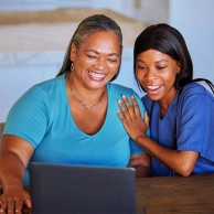 A senior woman and a female caregiver looking to a laptop