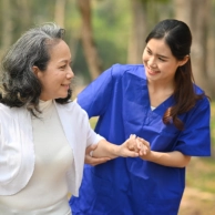 A female caregiver assisting a senior woman to walk