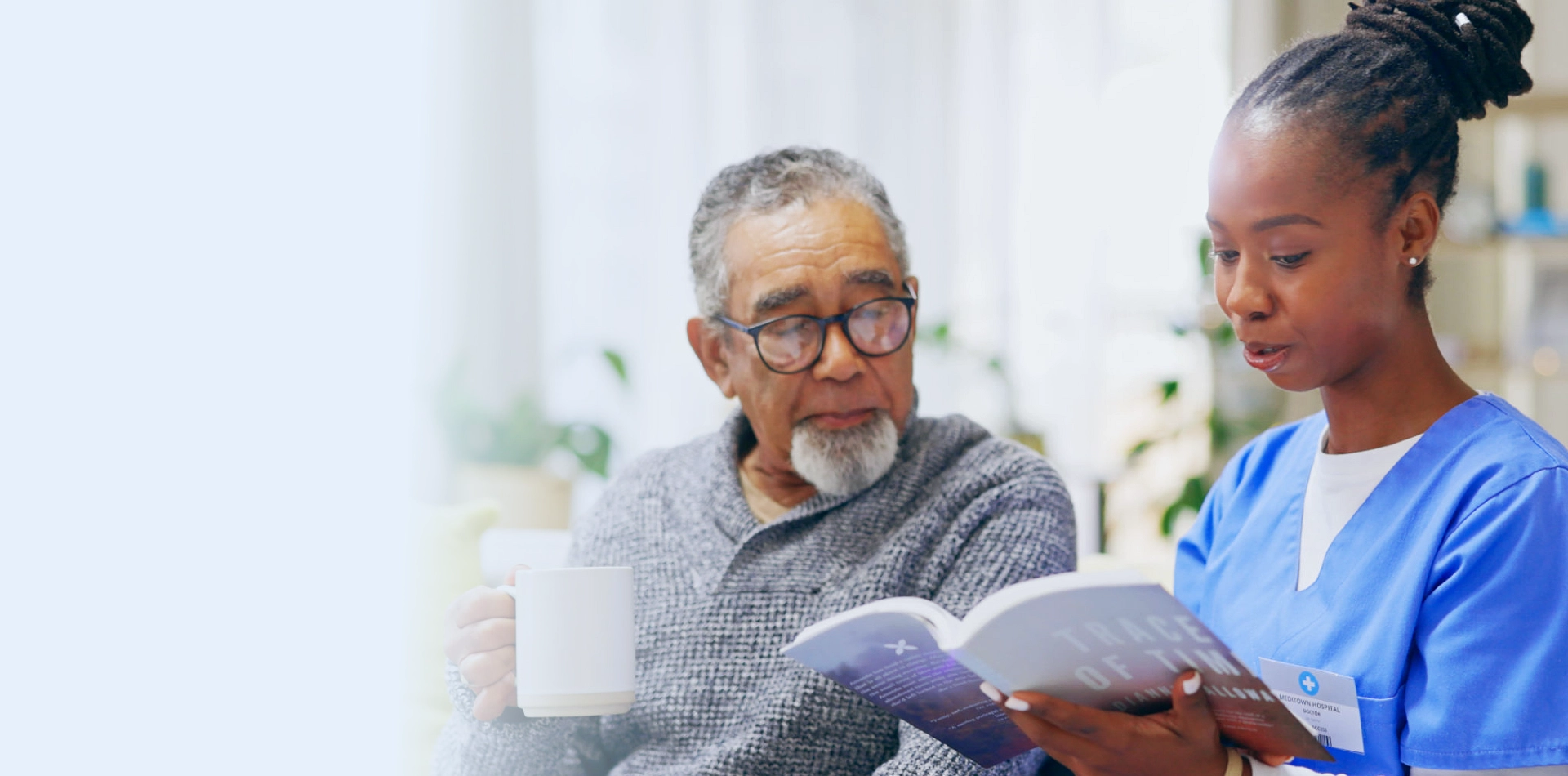 A senior man and a female caregiver reading a book