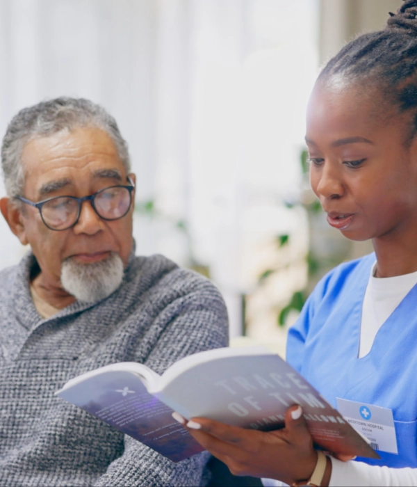 A senior man and a female caregiver reading a book