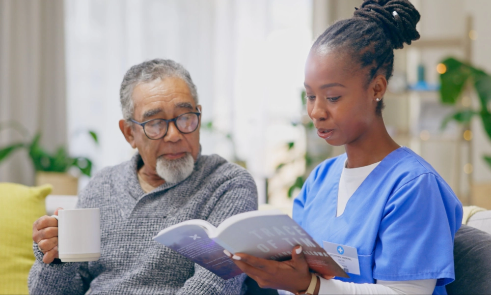 A senior man and a female caregiver reading a book