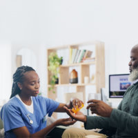 caregiver giving medicine to the elderly man