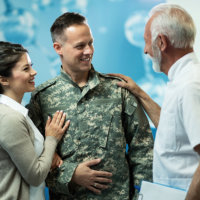  Happy military officer and his wife talking to a doctor in a hallway at clinic.